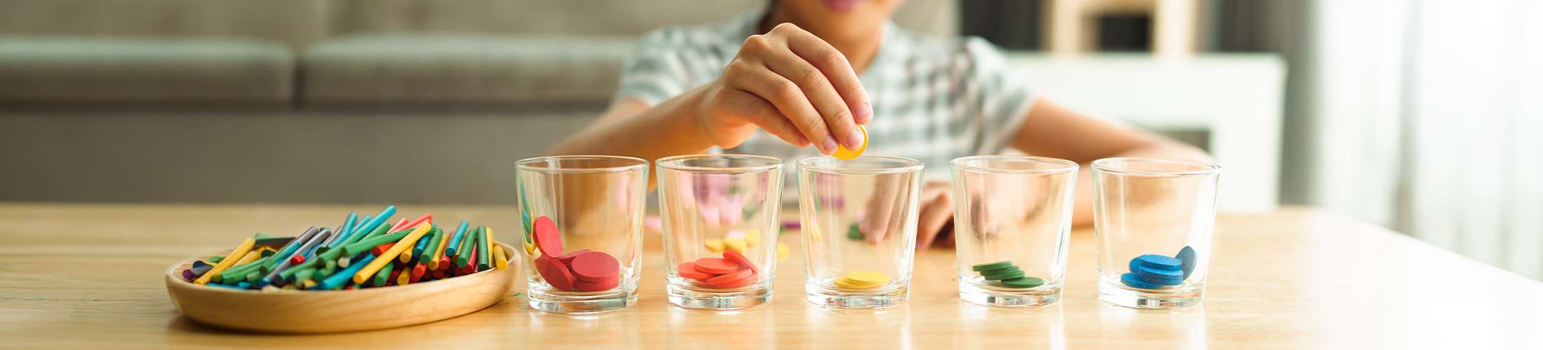 child sorting colours into glasses