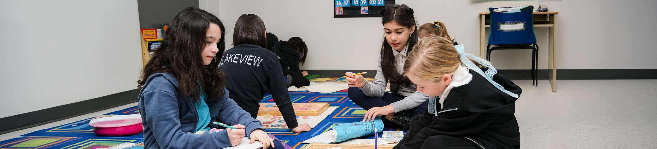 Elementary students working together on colourful mat